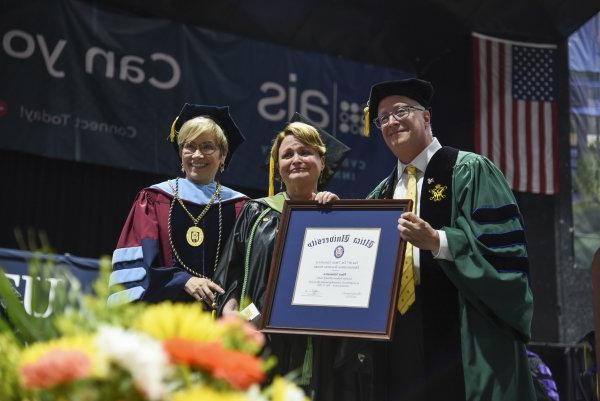 Professor of Occupational Therapy Mary Siniscaro stands between Provost Todd Pfannestiel and President Laura Casamento, holding her award at the 2023 Undergraduate Commencement Ceremony.